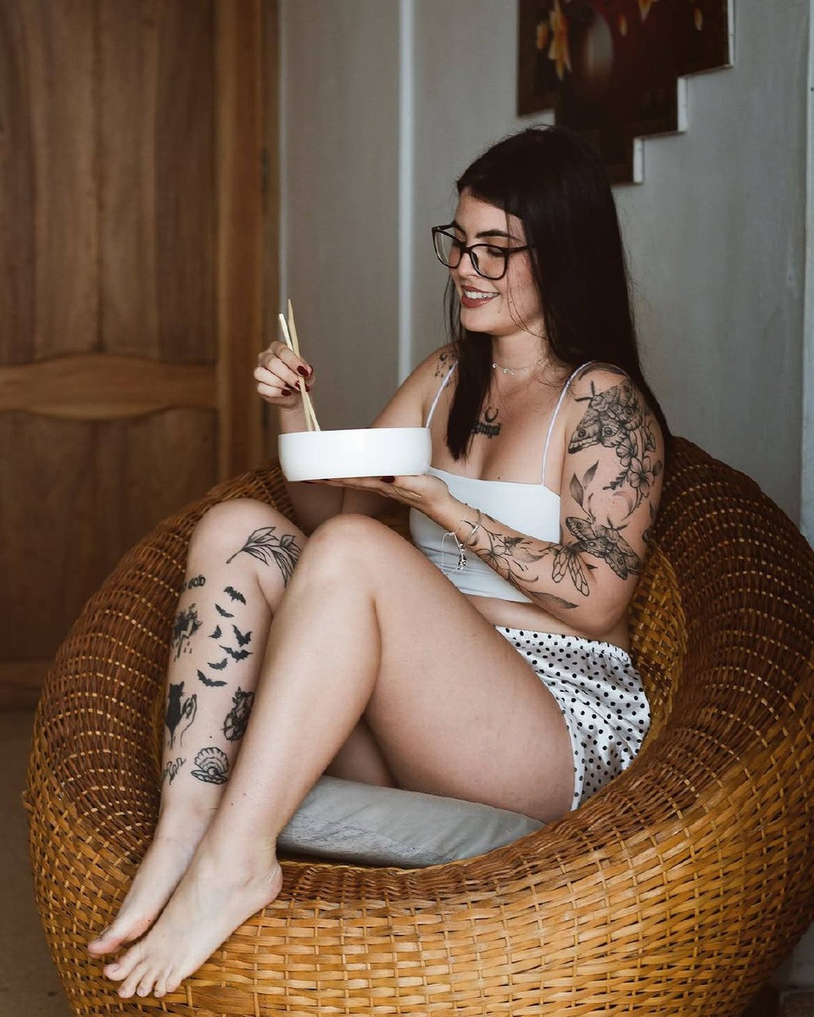 Retrato de mujer con tatuajes sentada, sonrisa espontánea